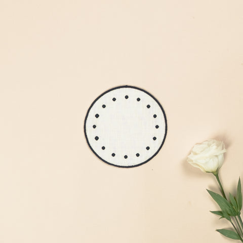 White round side plate with embroidered dark blue borders and dark blue dots, next to a white rose