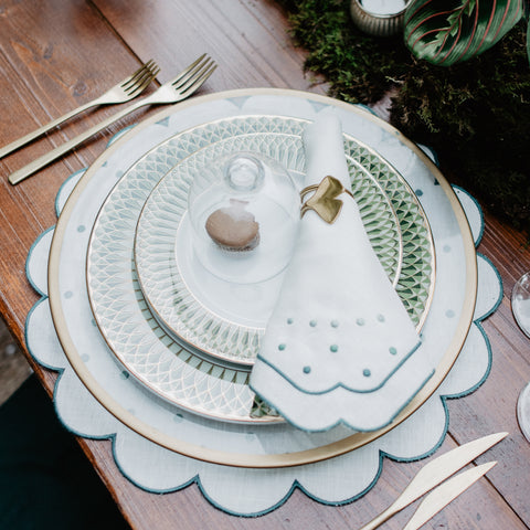 Festive table setting with matching napkin and placemat, both with green embroidered borders and embroidered green dot details