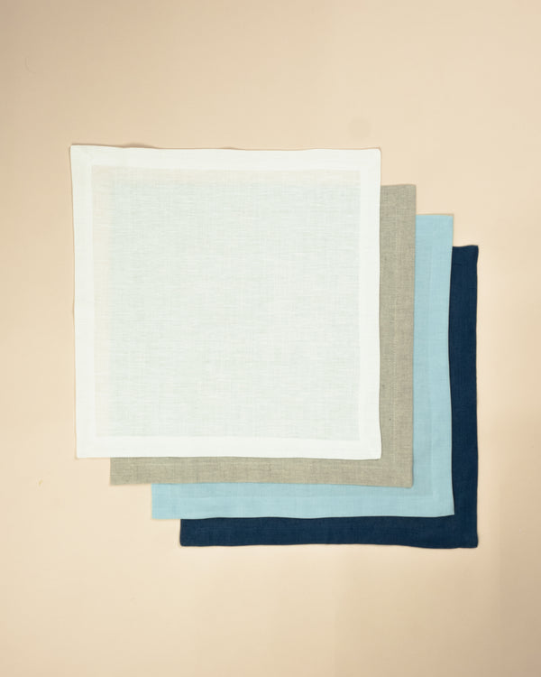 Set of four plain colour napkins, one white, one beige, one light blue, one dark blue