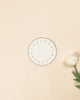 White round side plate with embroidered beige borders and beige dots, next to a white rose