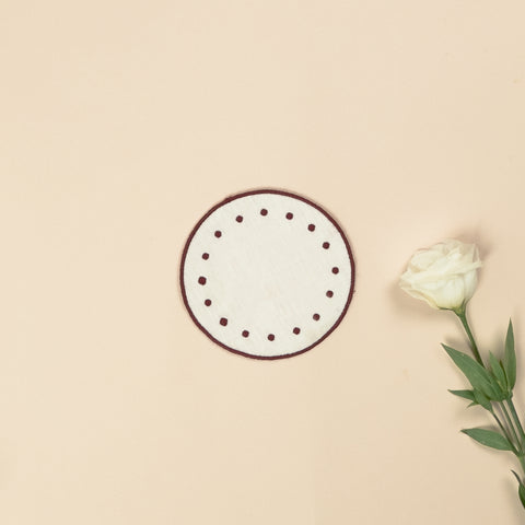 White round side plate with embroidered bordeaux borders and bordeaux dots along the edge, next to a white rose