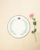 Round placemat in white with embroidered bordeaux border and a bordeaux scarab and green foliage embroidered
