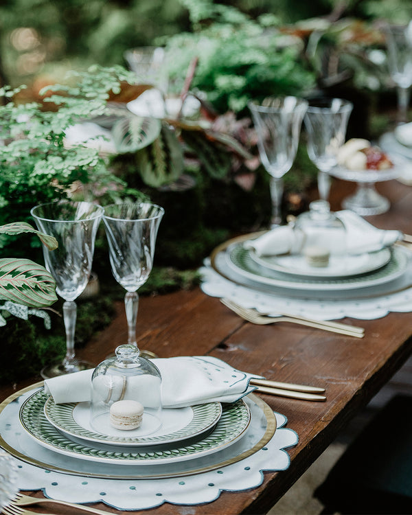 Festive table setting with a green theme with matching napkin and placemat, both with green embroidered borders and embroidered green dots details