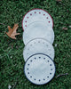 Set of four round side plates, all in white but with blue, bordeaux, beige and white colours on the embroidered edge and on the embroidered dots along the edge
